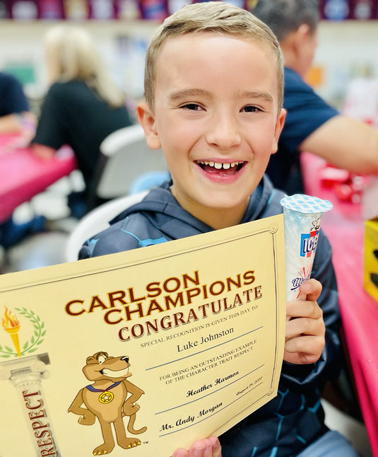 Luke holding an award at school and smiling